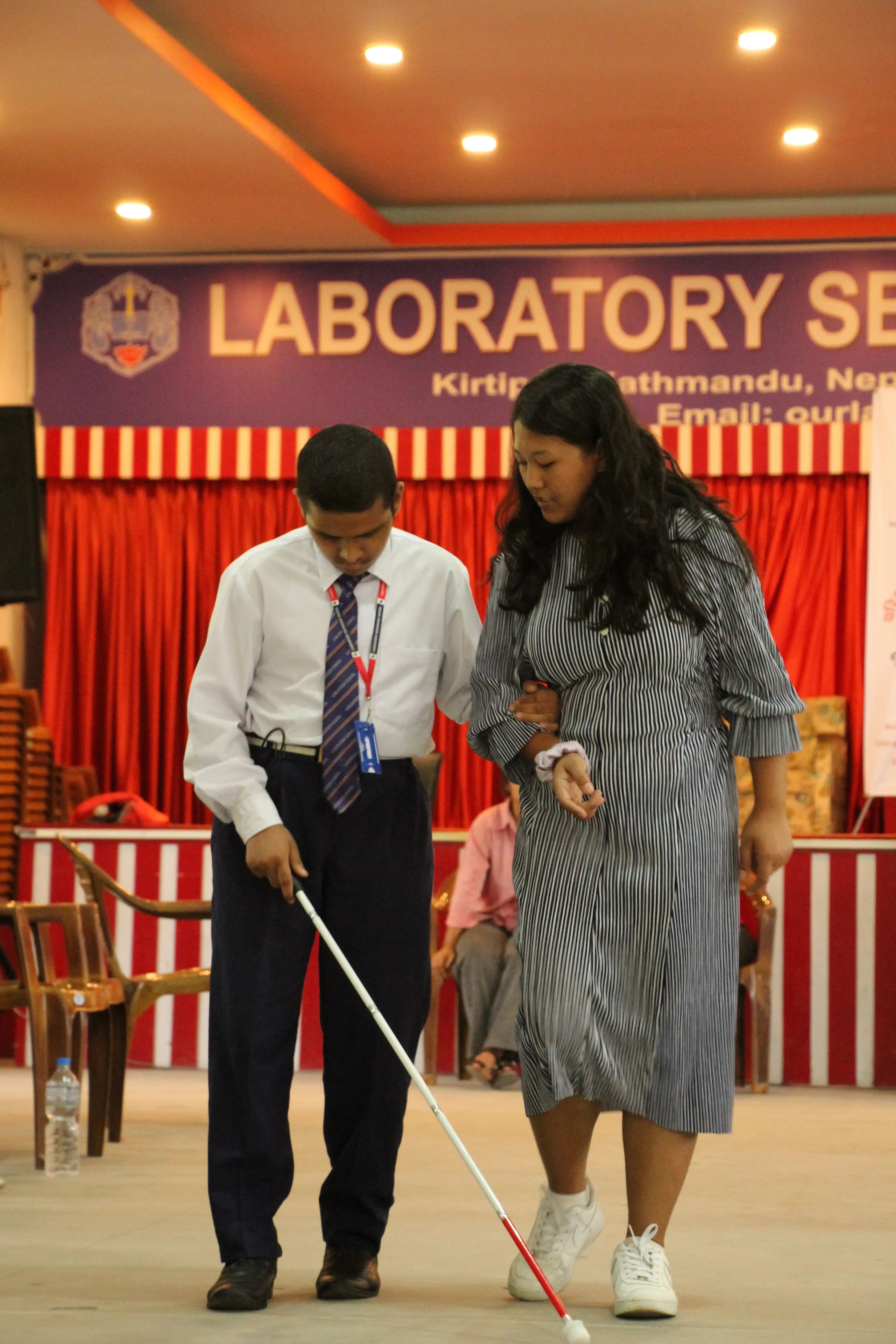 Anjali Maharjan - one of the guides to participants with visual disabilities is explaining and supporting her pair to use his white cane.