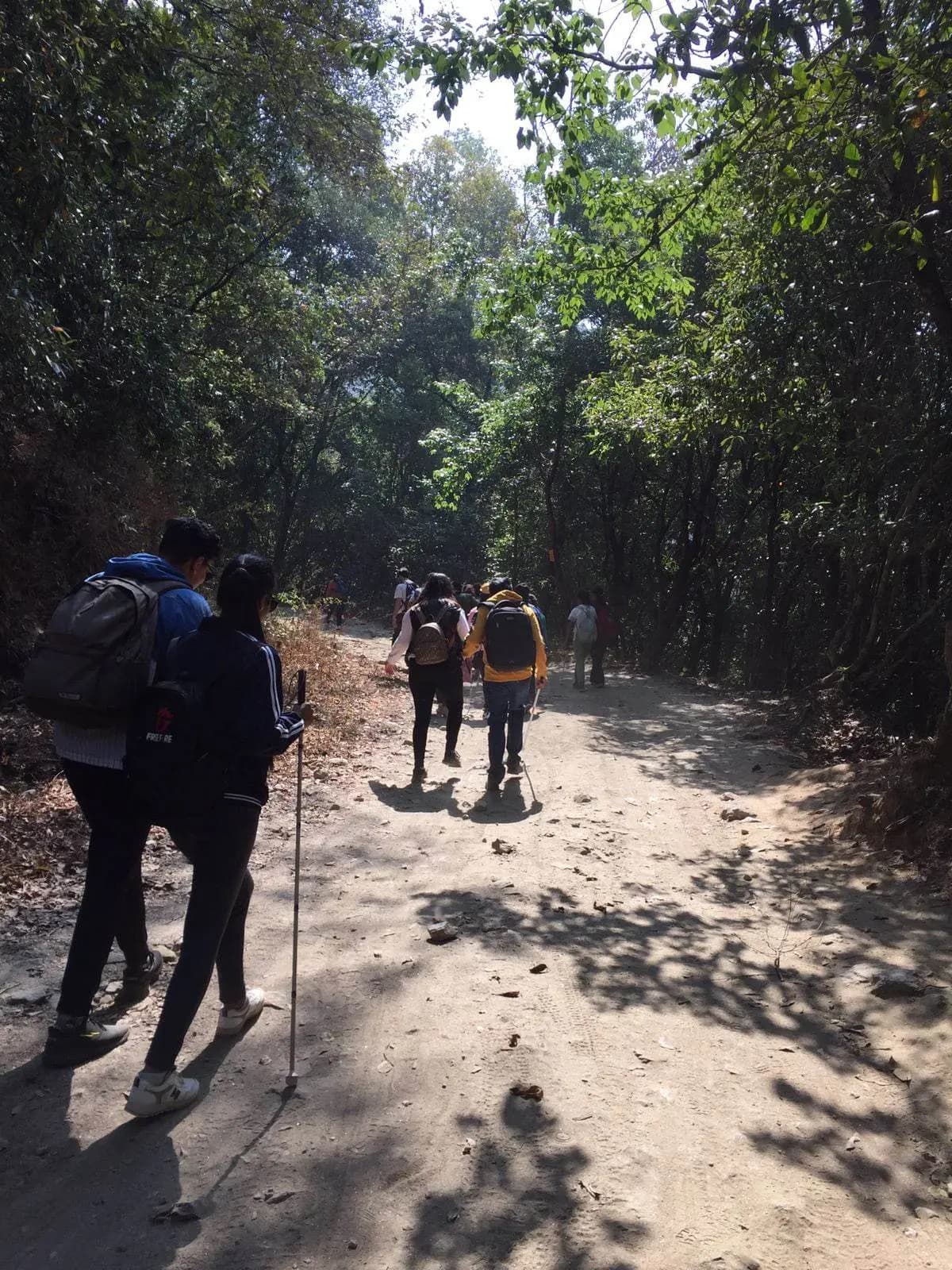 All the participants are hiking through the forest of Shivapuri – Nagarjung National Park. In the background green trees are observed.