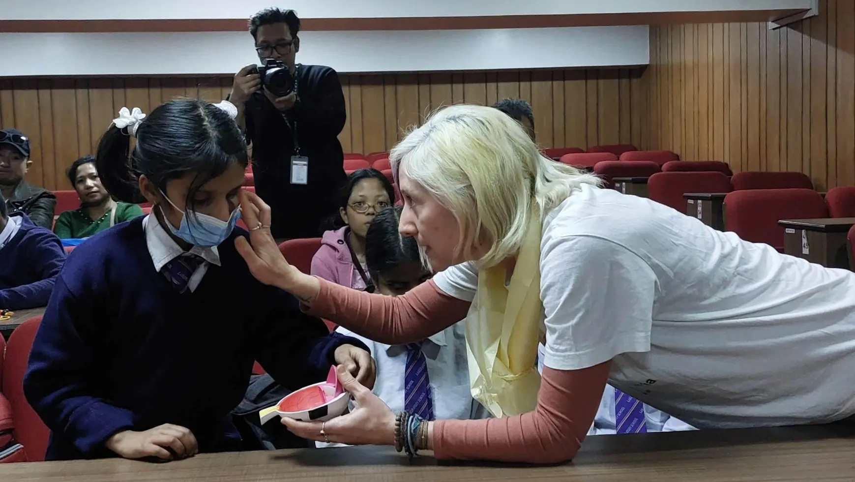 Dr. Cristina Gomez Vicente explaining the child with visual disability about the low vision by making her touch the 3D eye model.