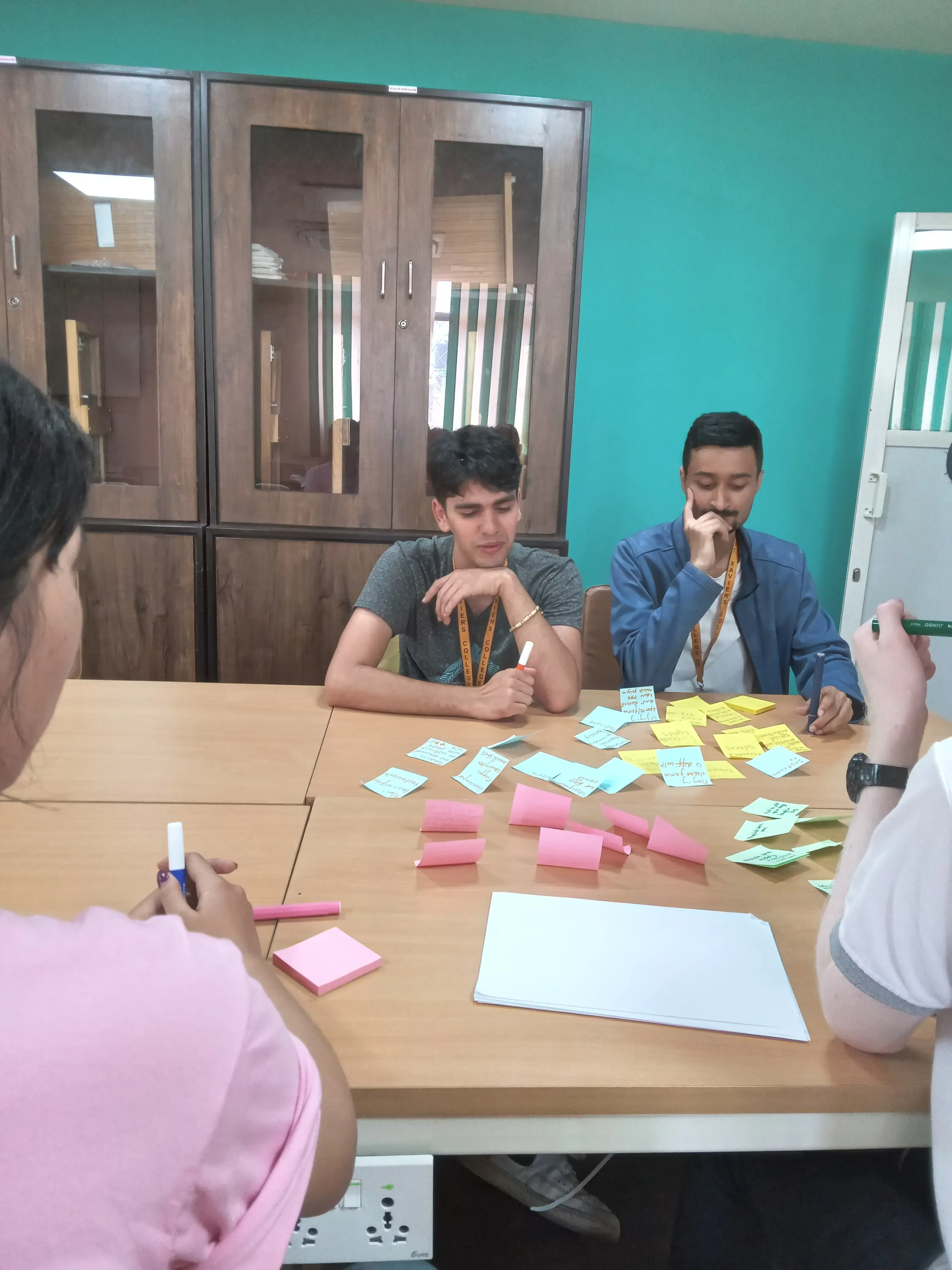 A picture where two of the dedicated team members of 3D design class are observing the sticky notes that were pasted on the table.