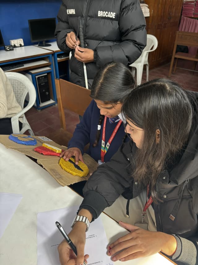 A girl is exploring 3D model of Traffic Signs and Project member Khushi Subedi is observing her and noting down her analysis.