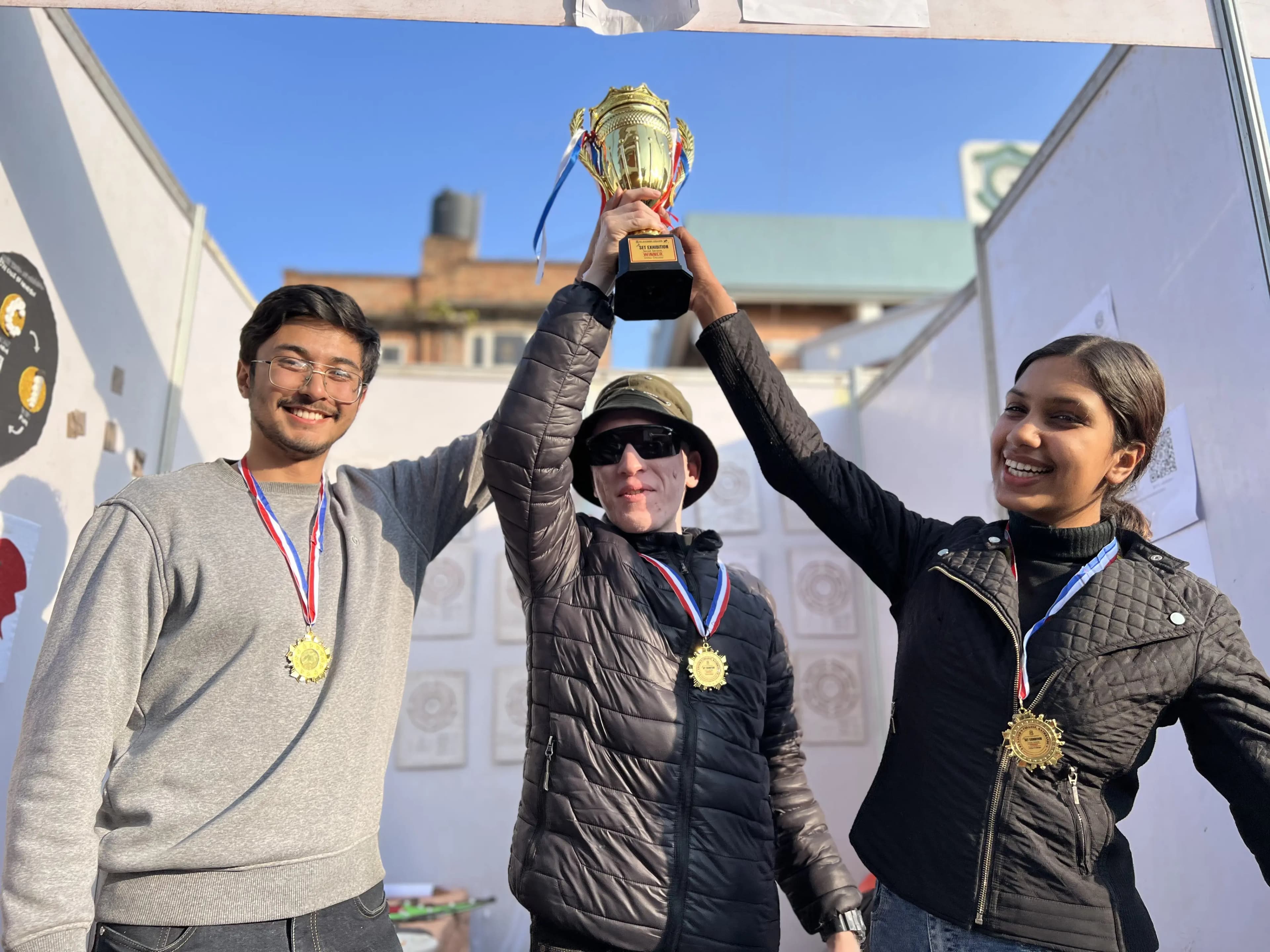 Project members Karmendra Shrestha, Joon Shakya and Sanskriti Pokharel are jointly lifting the winner's trophy of SET exhibition Social Service category.