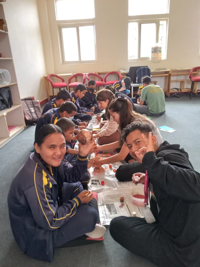 All the children are painting the planets as a group activity and the interns are supporting them.