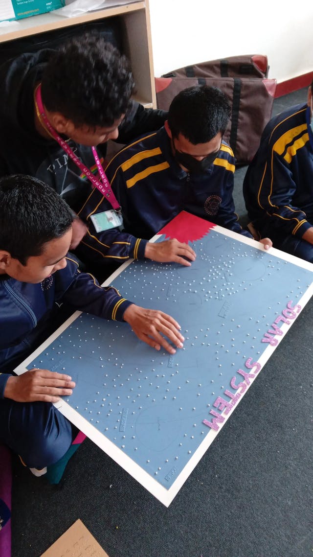 Children are touching the solar system board.