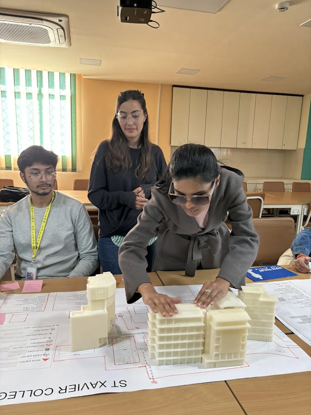 CFC member with visual disability Samjhana Rijal is perceiving the 3D maqueta of St. Xavier's College. On the right, project member Karmendra Shrestha and Valeria Mullar is observing her.