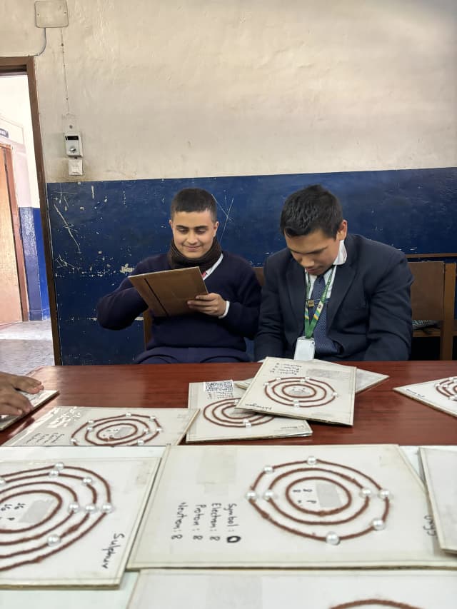 Two of the male participants are observed in the picture where participant on left is perceiving 3D model of atomic structure.