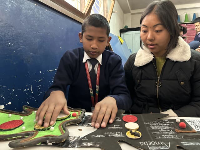 A boy is exploring the 3D model of Amoeba and project member Romee Jijicha is observing him.