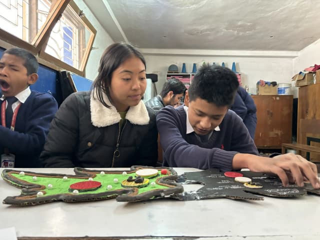 A boy on the right is exploring the 3D model of Amoeba. Project member Romee is observing him and another boy is seen on the left part of the image.