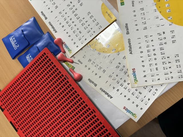 A picture displaying slates, styluses and Braille alphabet chart to learn the script.