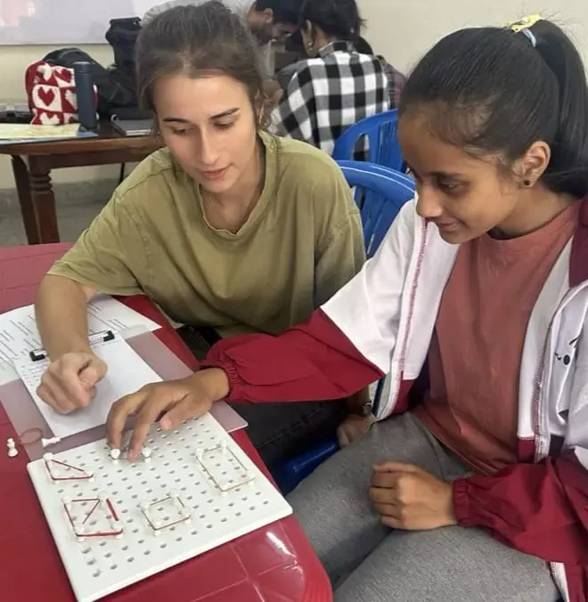 A female participant with visual disability is interacting with the 3D geometrical board. Our Intern Design Instructor (2024/25) Gala Cervera is observing her.