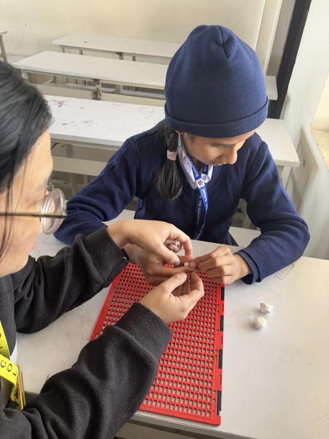 A picture of our project member Sanskriti Ghimire is teaching one of the female students with visual disability to use the 3D customizable stylus.