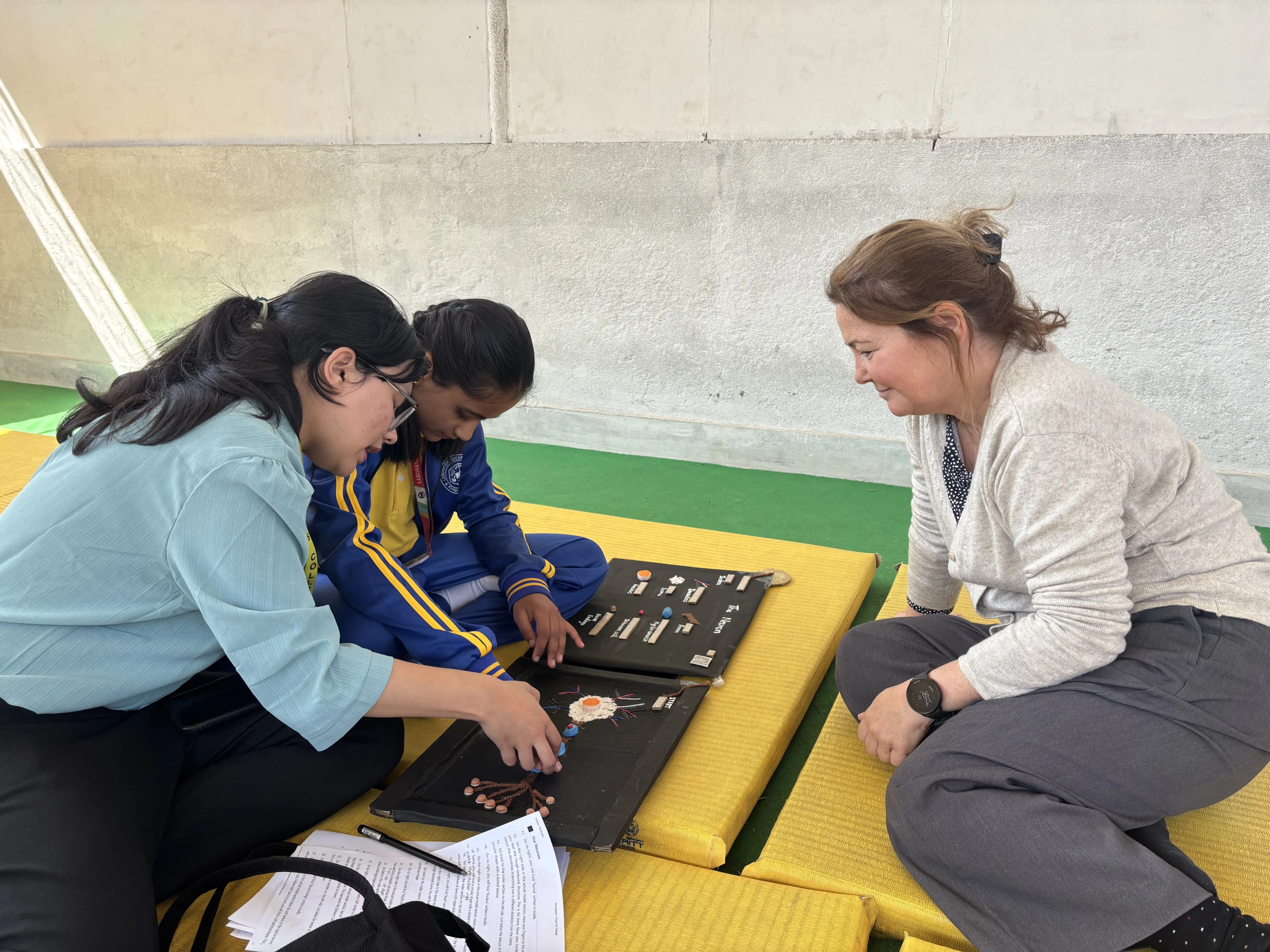 A picture showing a girl with visual disability touching the 3D model of Neuron where one of our project member Sanskriti Ghimire is supporting her. Ana – the exchange staff is observing them.