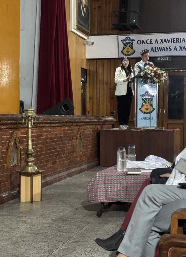 Our Public Relation & Philanthropy Officer, Mr. Sangam Khadka and Design Support Officer, Ms. Khushi Subedi, presenting about Project Wings to Dreams from the podium.