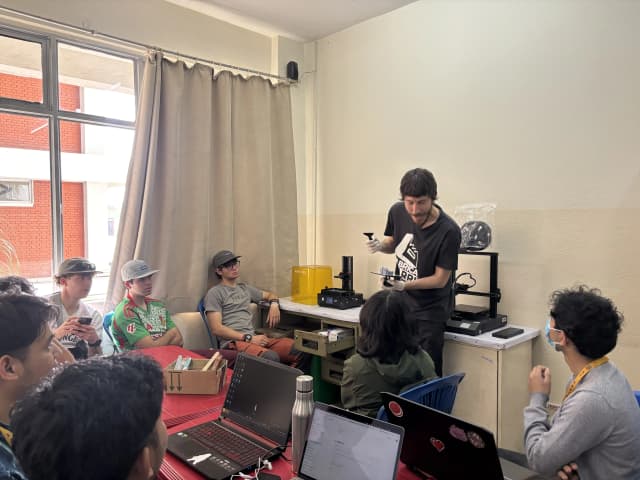 Mr. Miquel Cañada is holding the printed modular stylus and showing it to the participants. In the background both FDM 3D printer and Resin printer can be observed.