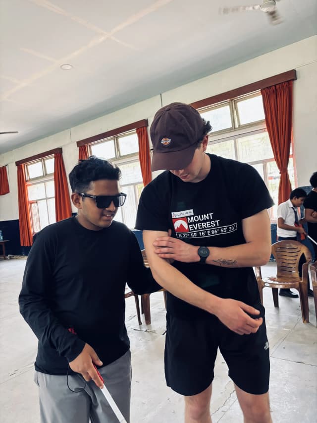 One of the Spanish interns, Mr. Tomas Edgar Requena is explaining one of the participants with visual disability to hold his arm. The participant with visual disability is also holding a white cane in his other hand.