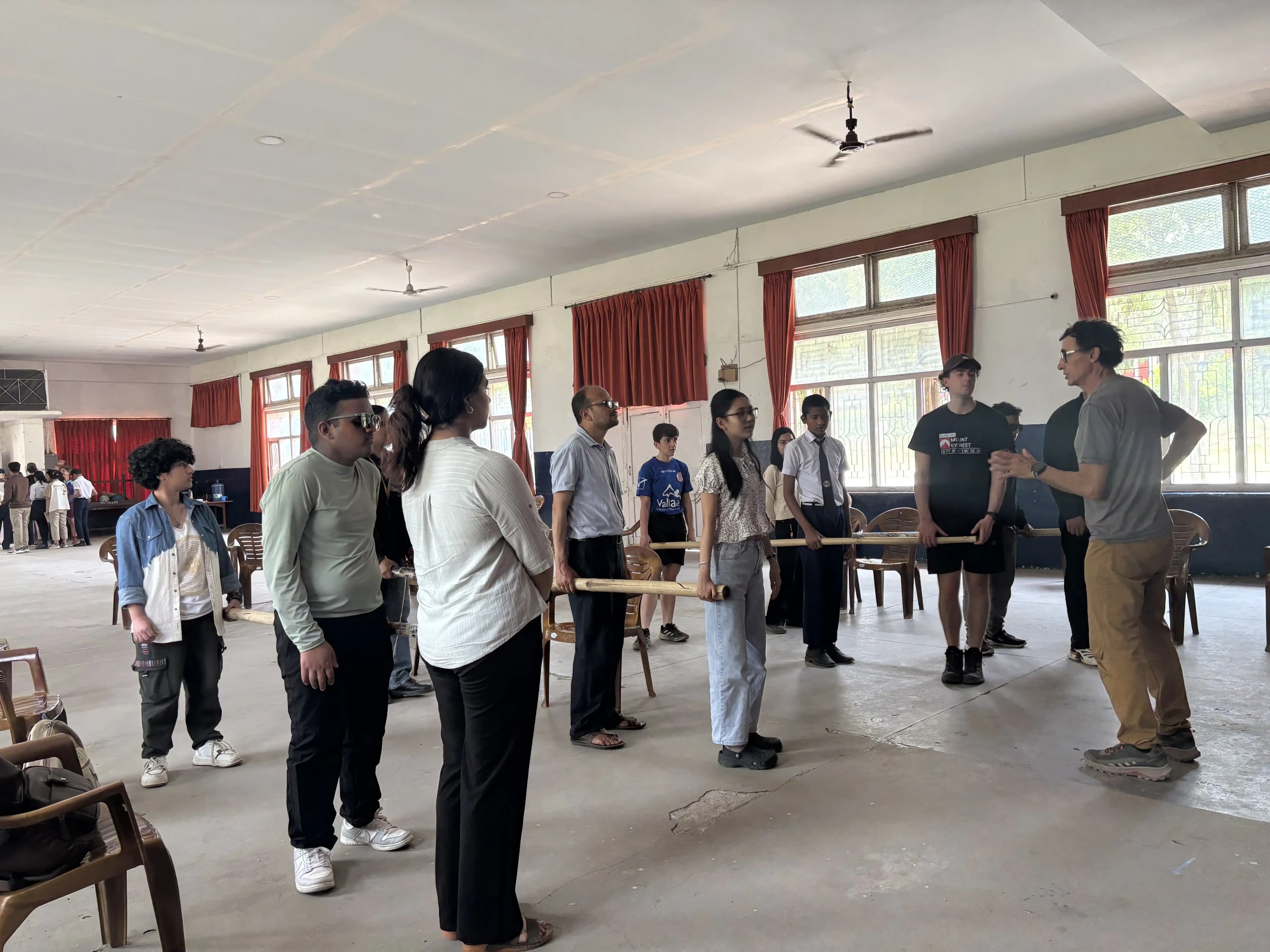 One of the facilitator, Mr. Alfonso Xosé González Cabarcos is instructing all the participants who are holding the long sticks in groups inside the training hall.
