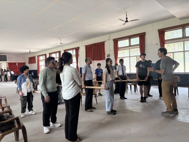 One of the facilitator, Mr. Alfonso Xosé González Cabarcos is instructing all the participants who are holding the long sticks in groups inside the training hall.