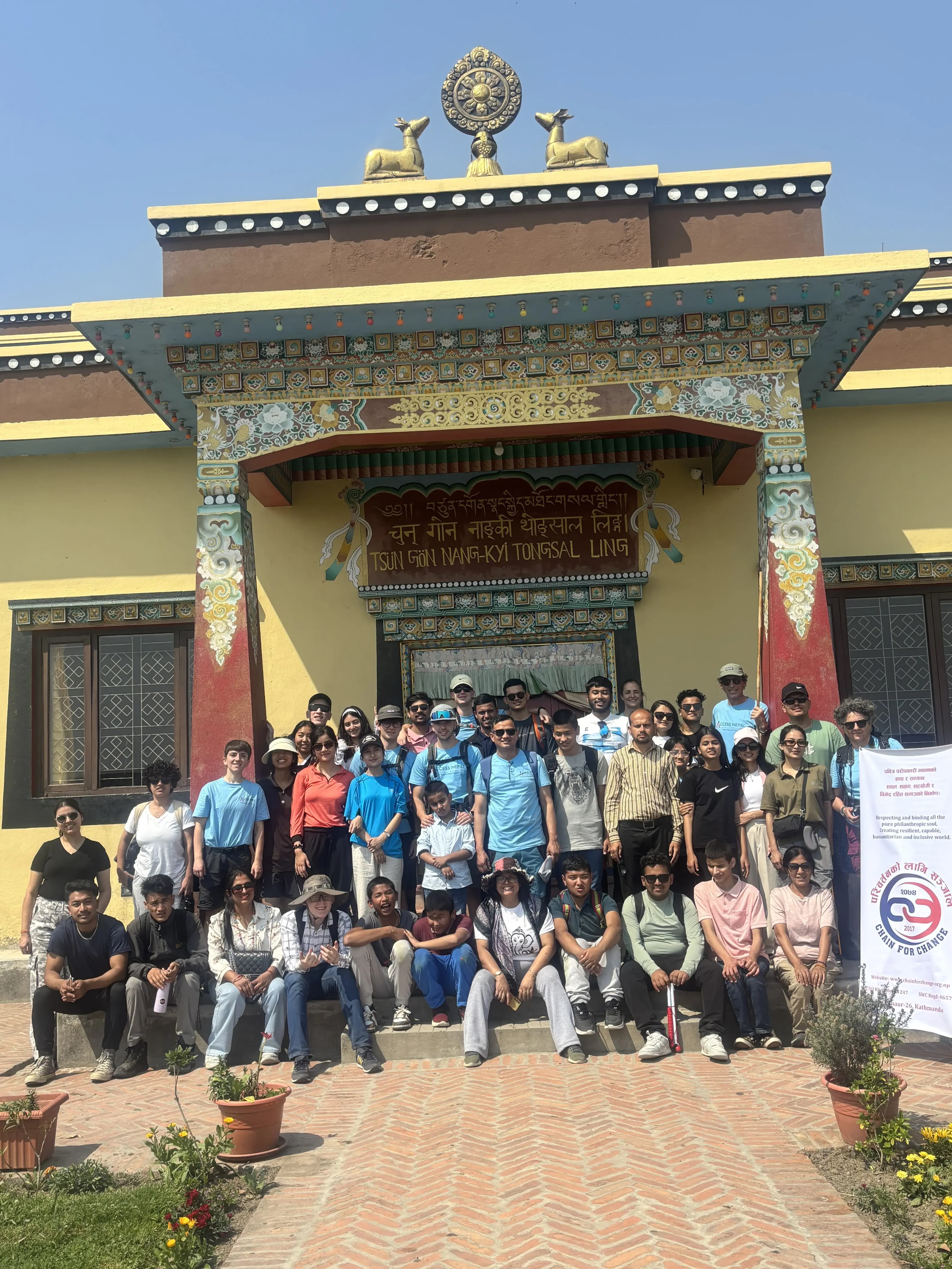 A group picture of around 42 individuals including project members, teachers and students with visual disabilities from Lab Schools, Spanish volunteers and facilitators, representative from Access Nepal and members of CFC. On the right, there is the banner of CFC and on background the entrance to the stupa is observed.