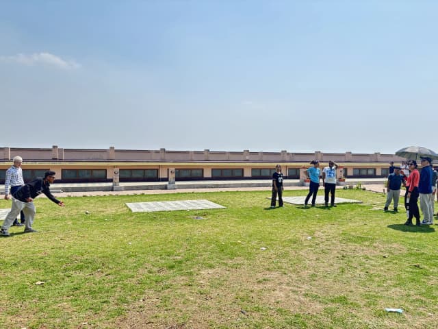 A group of students, members and some Spanish facilitators and interns are playing in the ground. One of the CFC members is throwing the sound ball.