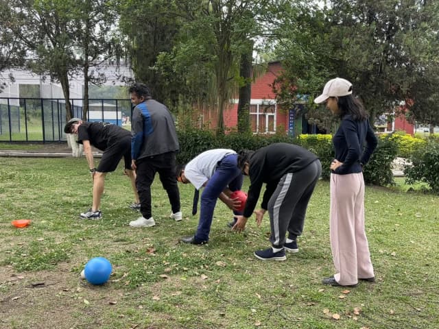 3 different lines of participants are passing the ball between their legs from the start to end in their respective rows.