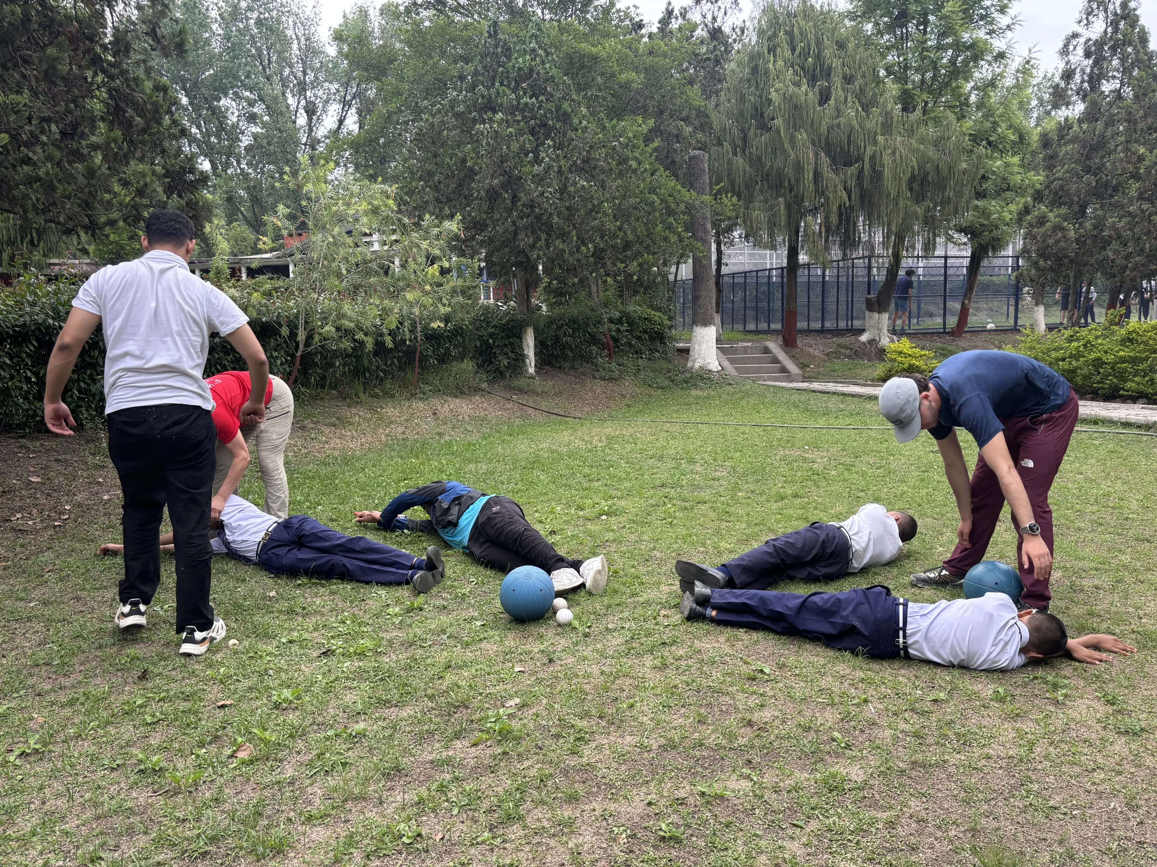 4 of the students with visual disabilities are learning the technique to defend the goalball. Other facilitators and project members are guiding them.