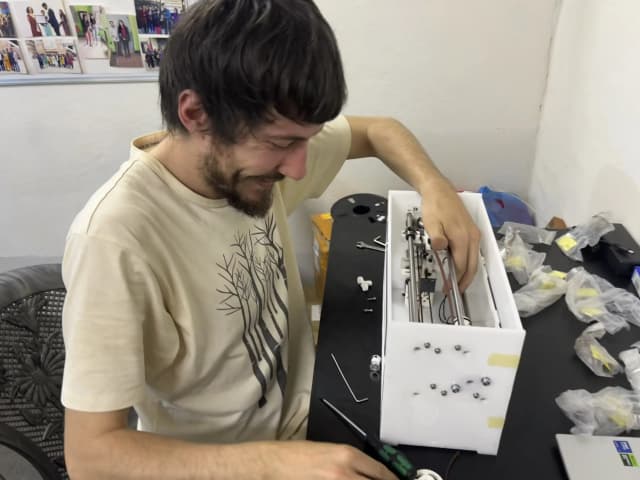Mr. Miquel Cañada is building a Nepal's 1st DIY braille printer. In the background, some tools and spare parts are placed in the table.