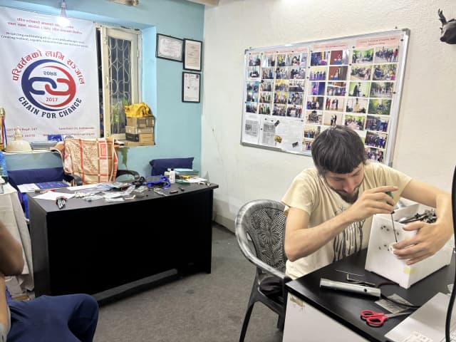 Mr. Miquel Cañada is building a Nepal's 1st DIY braille printer. In the background, the banner of CFC and office picture board is observed.
