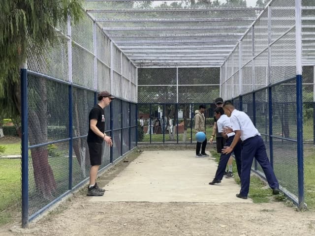 Two of the male participants with visual disabilities are practicing to throw the sound ball. In the background 2 of the Spanish interns and a project member is seen.