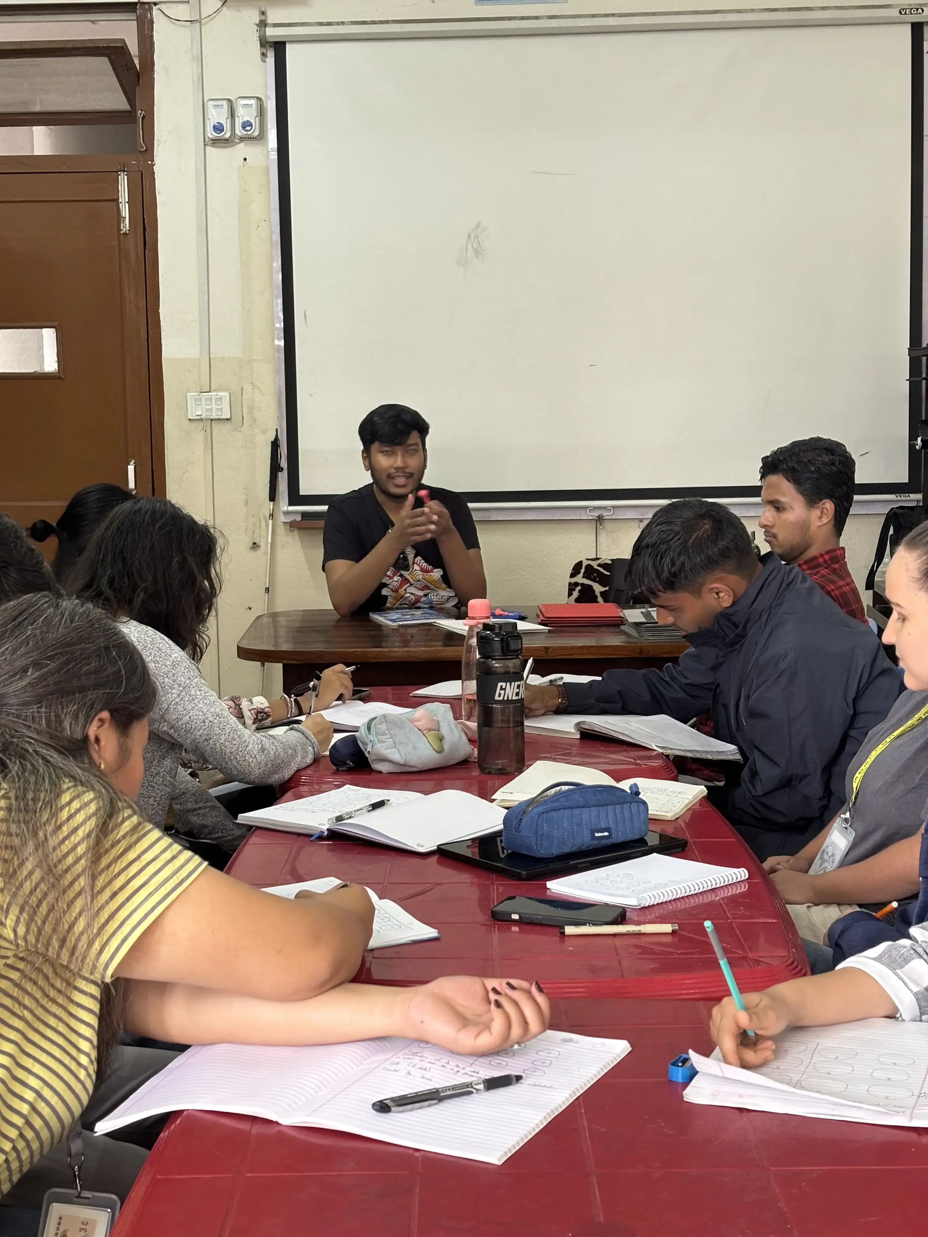 The facilitator of the event Mr. Abhishek Shahi is holding a stylus in his hand and explaining about it. The participants of the event are writing down the important points.