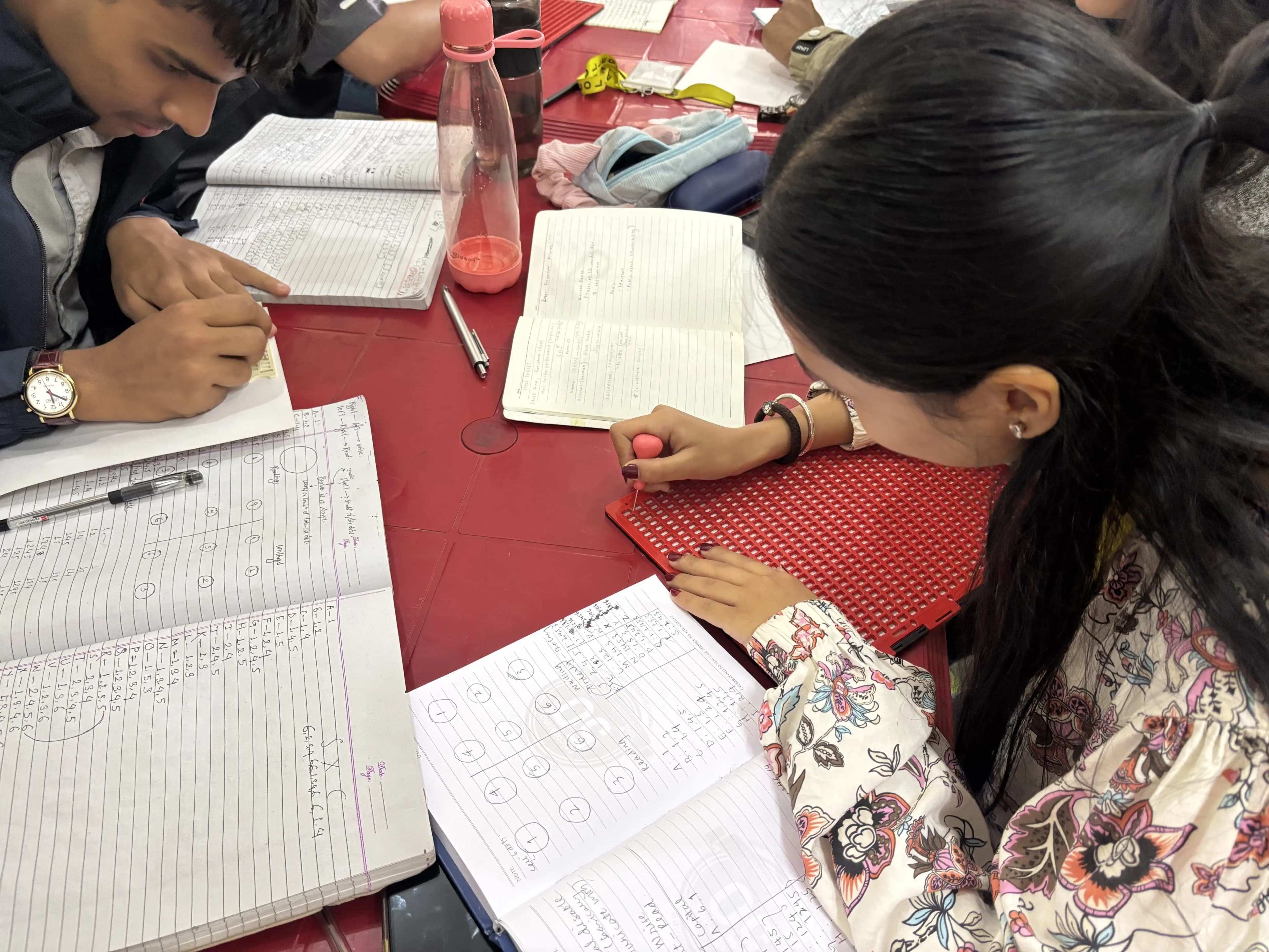Two of the project members (2025/26) are writing in braille using braille slates and styluses.