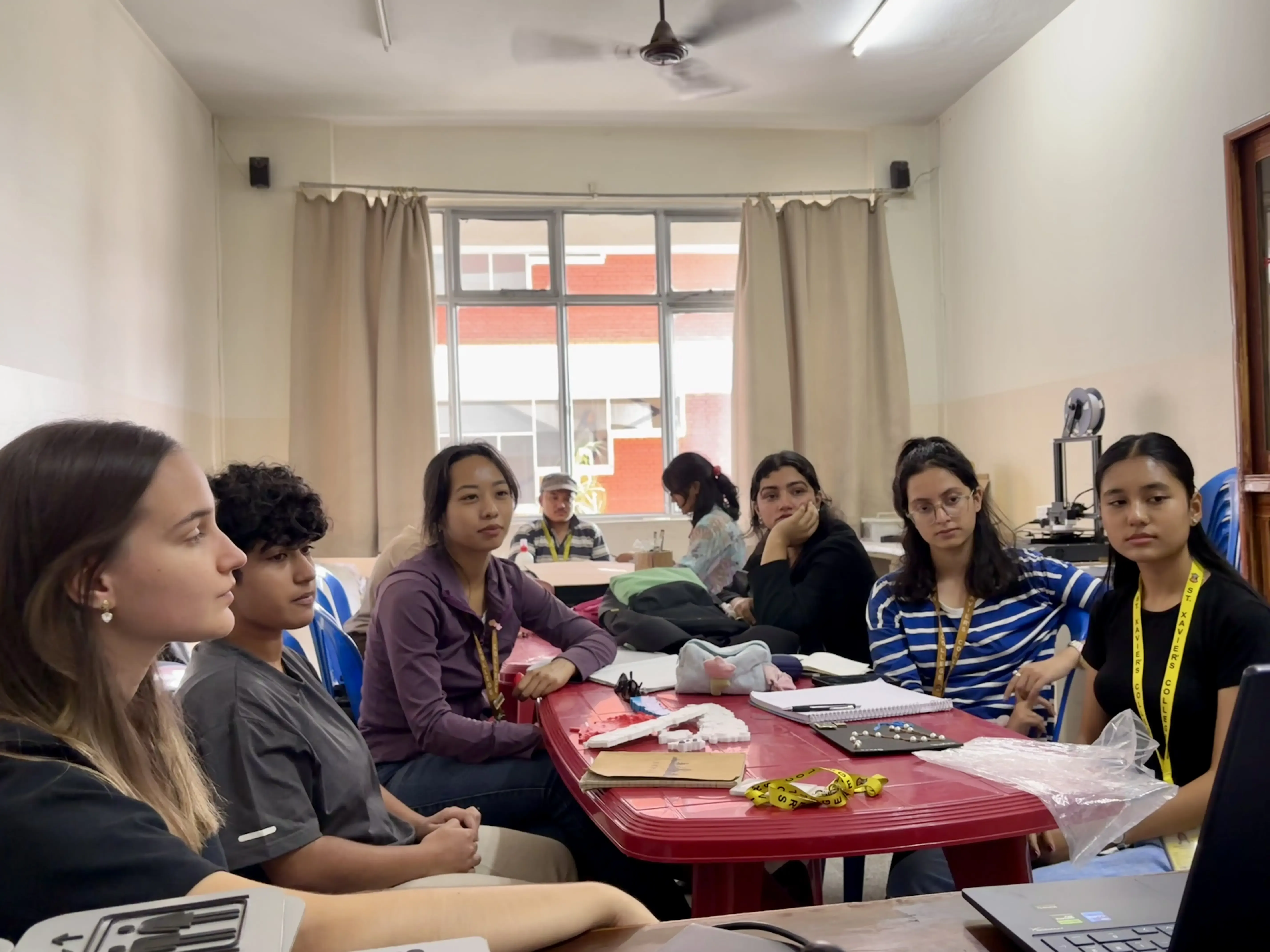 Around 6 participants are observing the laptop screen and listening to the facilitator.