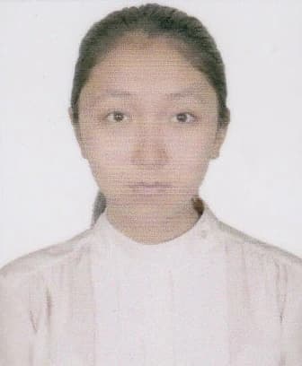 Young woman with light-brown skin and dark hair tied back, wearing a high-neck light-colored top, facing the camera with a neutral expression against a plain white background.