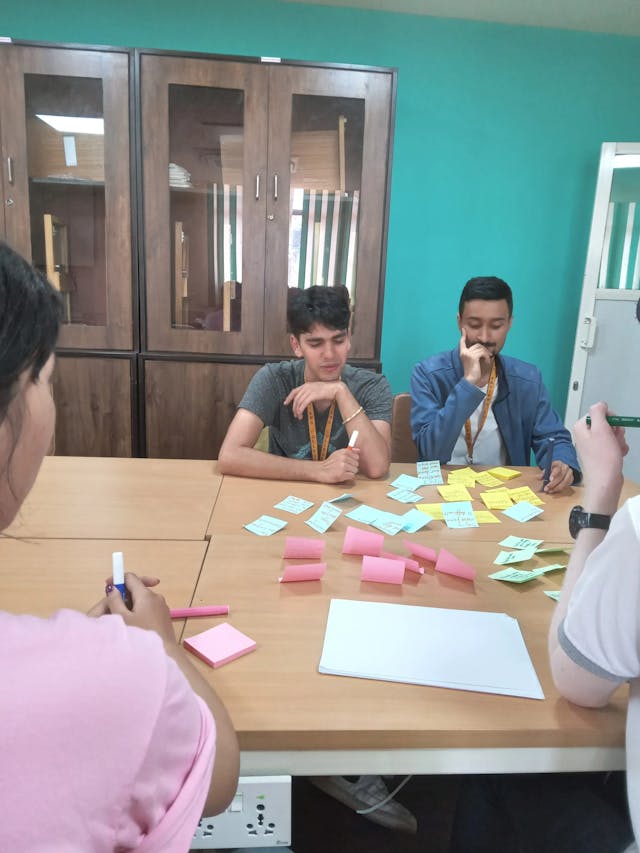 A picture where two of the dedicated team members of 3D design class are observing the sticky notes that were pasted on the table.
